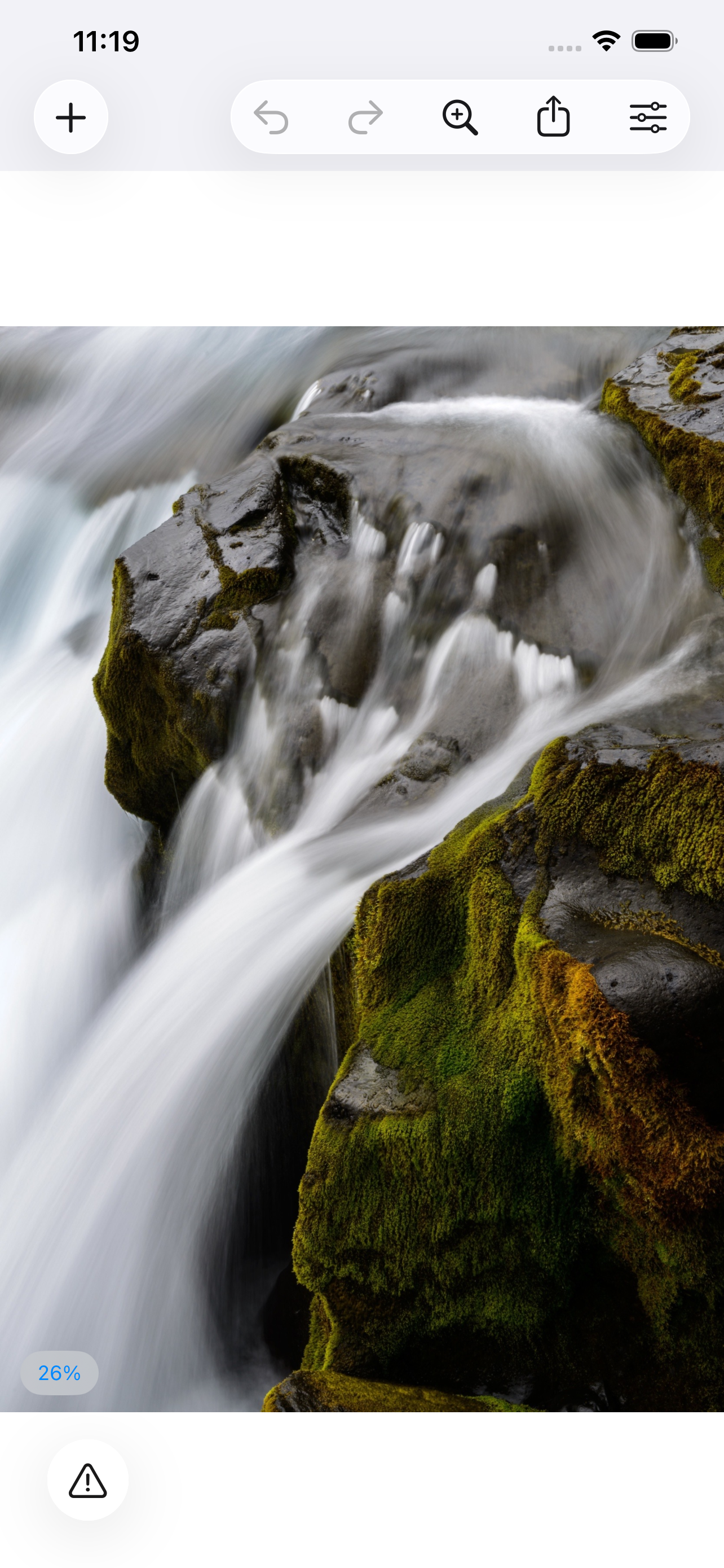 An image open on iPhone &mdash; a long-exposure photograph of water pouring over mossed rock, shown at 26% with undo, redo, zoom, share and the tool sheet in the toolbar